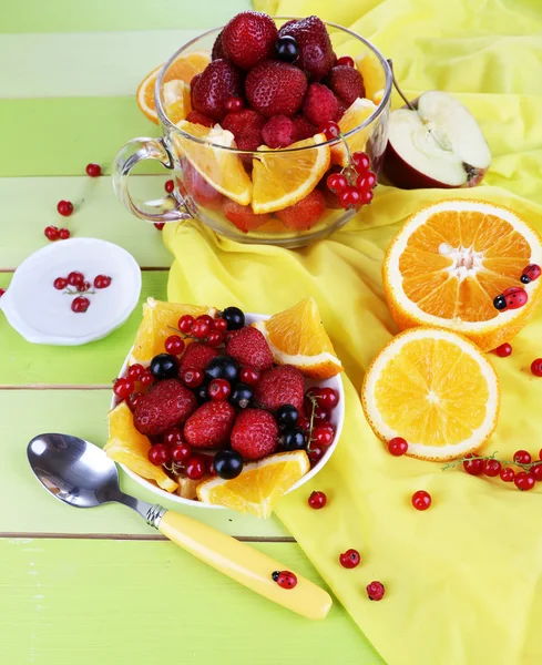 Useful fruit salad in glass cup and bowl on wooden table close-up — Stock Photo, Image