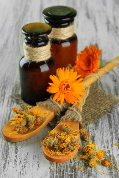 Medicine bottles and calendula flowers on wooden background — Stock Photo, Image