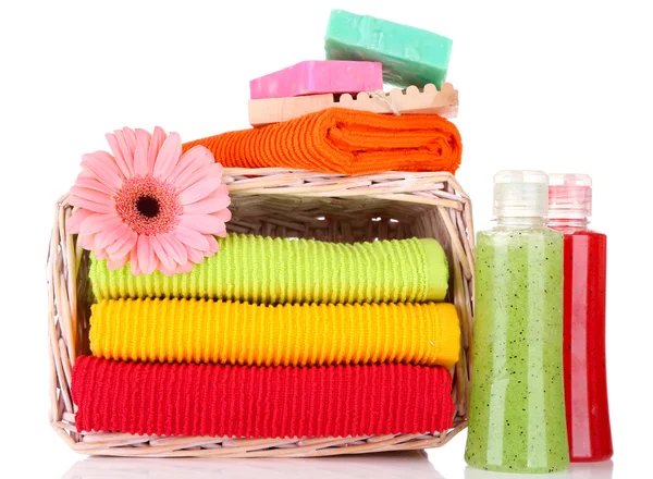 Colorful towels in basket and cosmetics bottles isolated on white — Stock Photo, Image