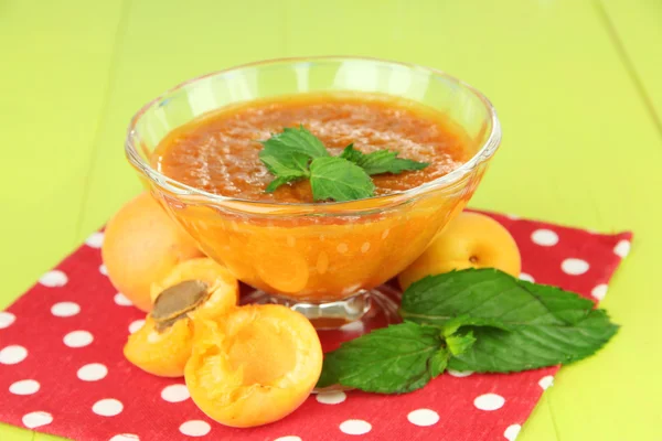 Marmellata di albicocche in ciotola di vetro e albicocche fresche, su fondo di legno — Foto Stock