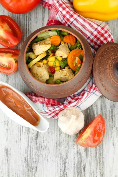 Gebakken gemengde groenten met kipfilet in pot, op houten achtergrond — Stockfoto