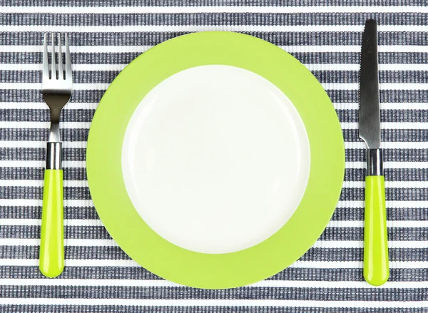 Ніж, кольорова тарілка та виделка на кольоровому фоні — стокове фото