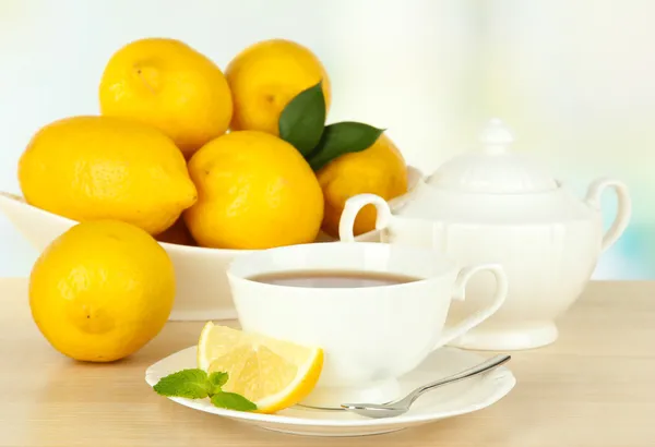 Egy csésze tea citrommal az asztalon, könnyű háttér — Stock Fotó
