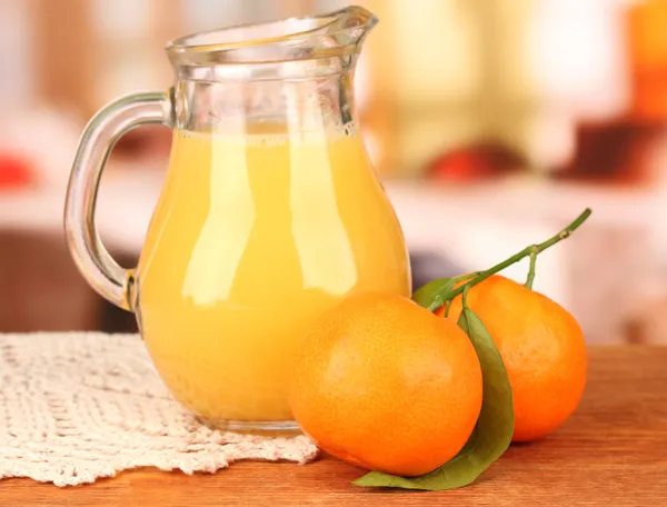 Caraffa piena di succo d'arancia, su tavolo di legno su sfondo luminoso — Foto Stock