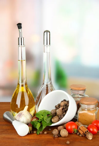 Composição de argamassa, garrafas com azeite e vinagre, e ervas verdes, sobre fundo brilhante — Fotografia de Stock