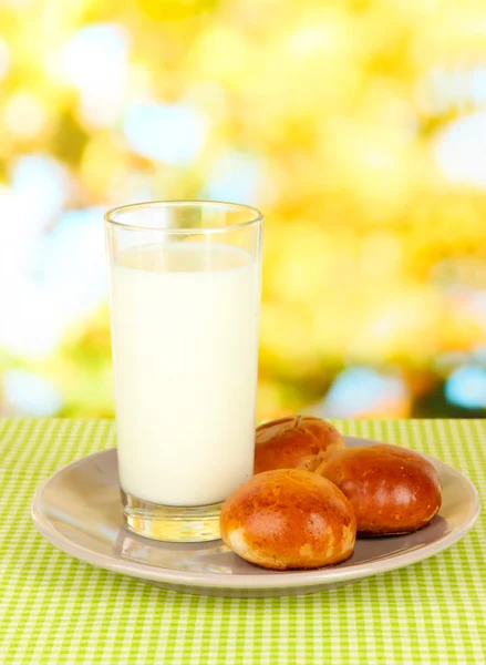 Bread roll and glass of milk on nature background — Stock Photo, Image