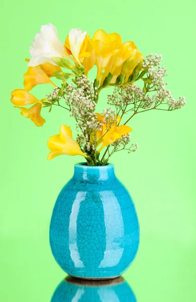 Красивый букет фрезии в вазе на зеленом фоне — стоковое фото