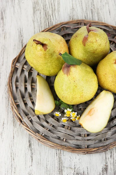 Pears on braided tray on wooden table — Stock Photo, Image