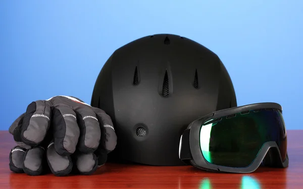 Winter sport glasses, helmet and gloves, on blue background — Stock Photo, Image