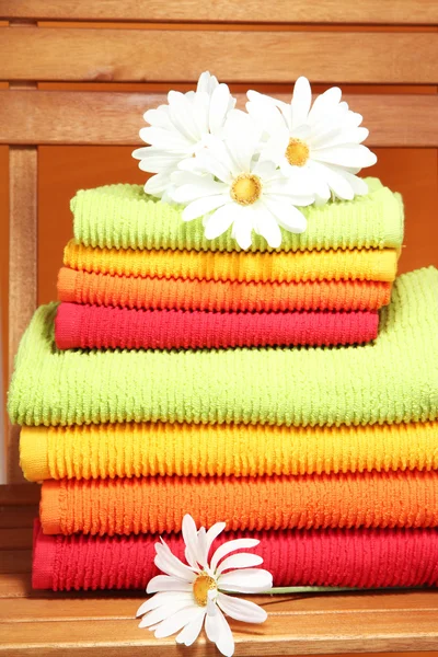 Towels and flowers on wooden chair on orange background — Stok fotoğraf