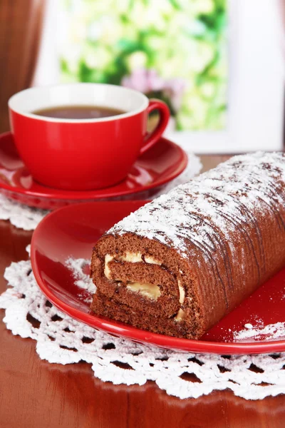 Rolo doce com xícara de chá na mesa no quarto — Fotografia de Stock