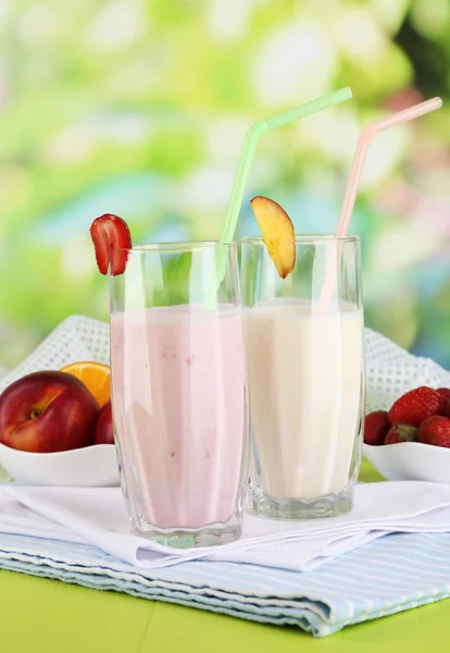 Deliciosos batidos de leche con fresas y melocotón sobre mesa de madera sobre fondo natural —  Fotos de Stock