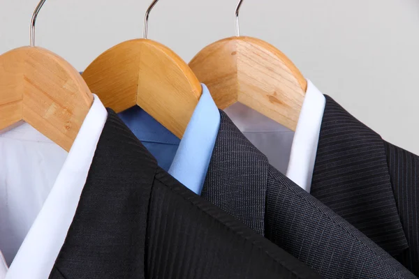 Suits with shirts on hangers on light background — Stock Photo, Image