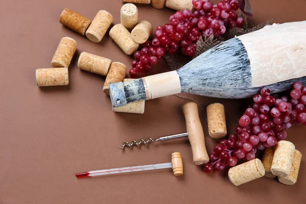 Old bottle of wine, grapes and corks on brown background — Stock Photo, Image