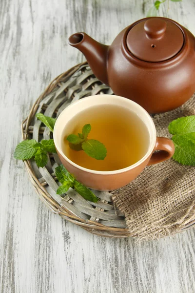 Teekanne und Tasse Kräutertee mit frischer Minze auf Holztisch — Stockfoto