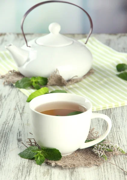 Theepot en kopje kruiden thee met verse munt bloemen op houten tafel — Stockfoto