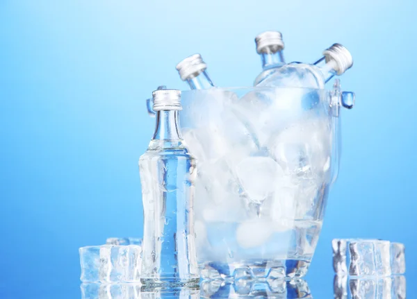 Minibar bottles in bucket with ice cubes, on blue background — Stock Photo, Image