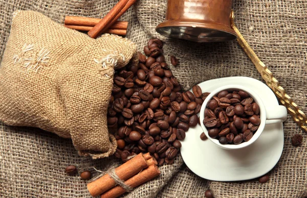 Koffiekopje en metalen turk op jute achtergrond — Stockfoto