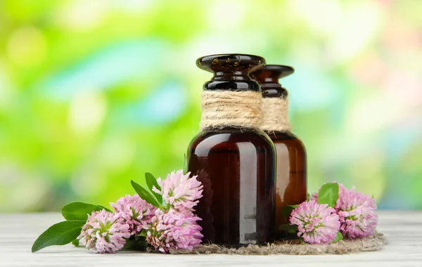 Flacons de médicaments avec fleurs de trèfle sur table en bois, à l'extérieur — Photo