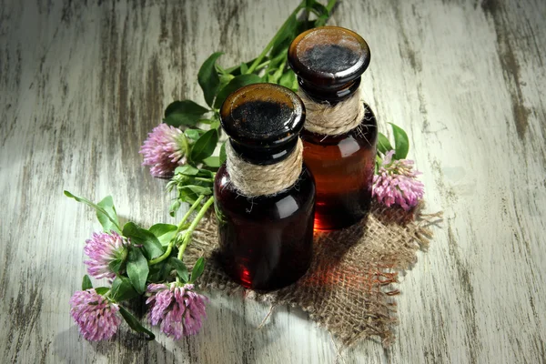 Medicin flaskor med klöver blommor på träbord — Stockfoto