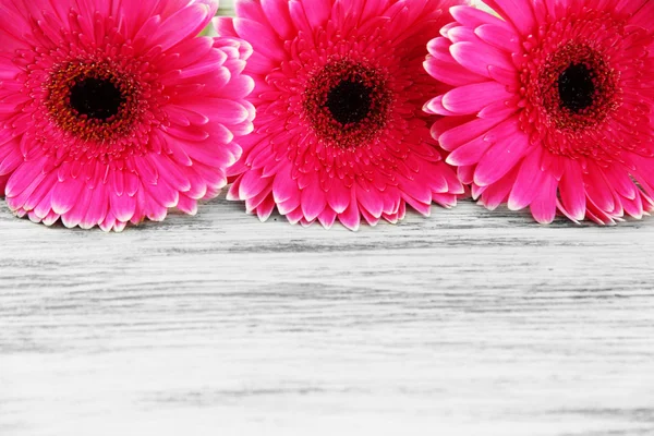 Hermosas flores de gerberas rosadas en mesa de madera —  Fotos de Stock