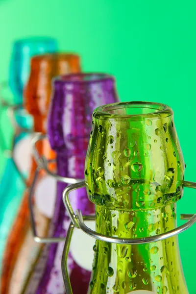 Kolorowe butelki na zielonym tle — Zdjęcie stockowe