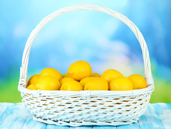 Limones maduros en canasta de mimbre sobre mesa sobre fondo brillante —  Fotos de Stock