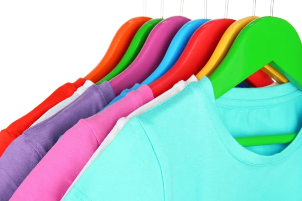 Different shirts on colorful hangers on white background — Stock Photo, Image