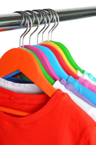 Verschillende shirts op kleurrijke hangers op witte achtergrond — Stockfoto