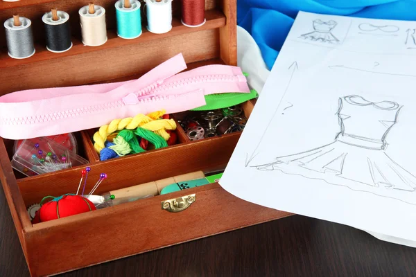 Kit de costura en caja de madera, tela y boceto en mesa de madera —  Fotos de Stock