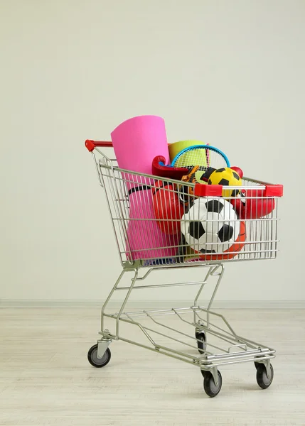 Shopping cart with sport equipment, on gray background — Stock Photo, Image