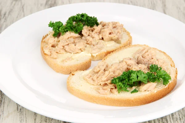 Tasty sandwiches with tuna and cod liver sardines, on white plate. on wooden background — Stock Photo, Image