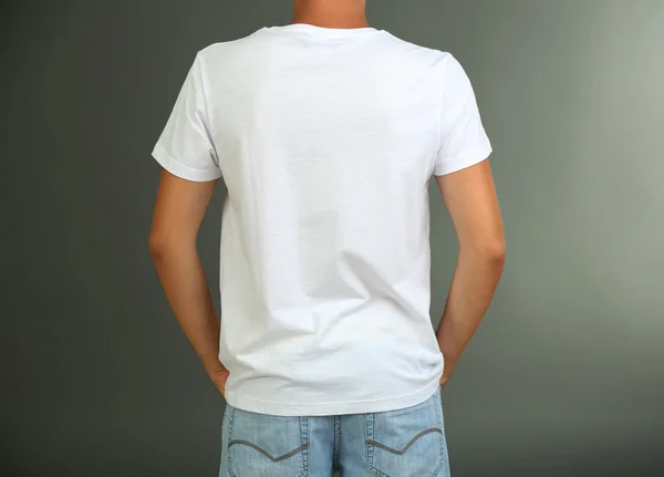 T-shirt su giovane uomo, su sfondo grigio — Foto Stock