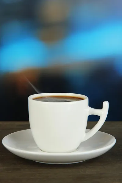 Taza de café sobre mesa de madera sobre fondo brillante — Foto de Stock