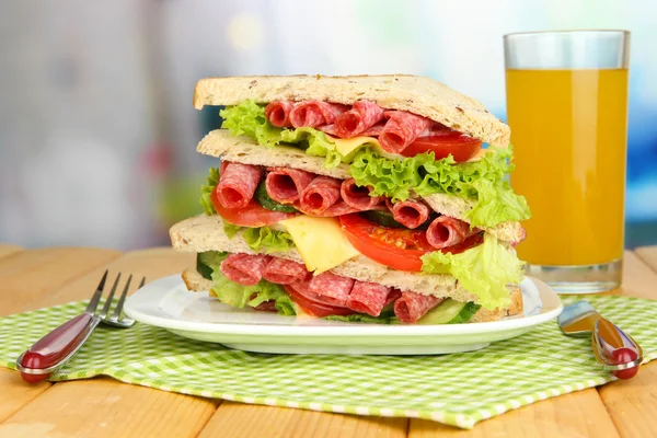 Huge sandwich on wooden table, on bright background — Stock Photo, Image