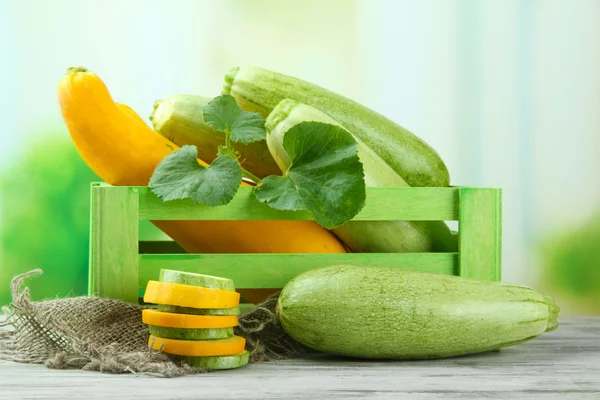 Sliced and whole raw zucchini in wooden crate, outdoors — Stock Photo, Image