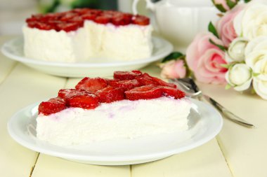 Cheesecake ahşap masa üzerinde beyaz tabak taze çilek ile