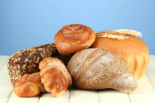 Composition with bread and rolls on wooden table, on color background — Stock Photo, Image