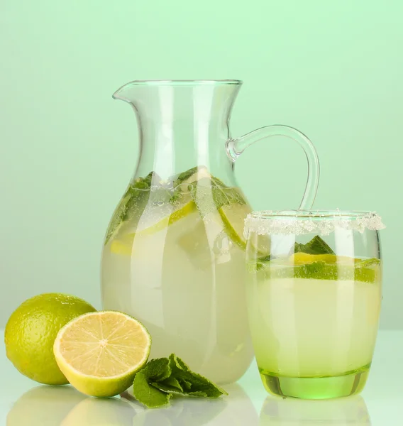 Lemonade in pitcher and glass on turquoise background — Stock Photo, Image