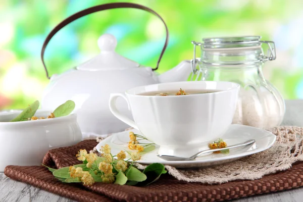 Tasse Tee mit Linde auf Servietten auf Holztisch auf Naturhintergrund — Stockfoto