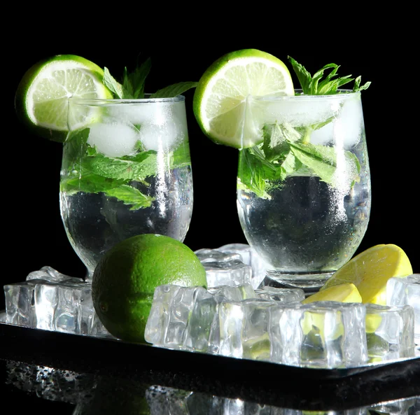 Glasses of cocktail with ice on metal tray on black background — Stock Photo, Image