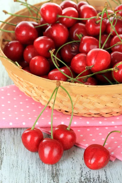 Kirschbeeren im Weidenkorb auf Holztisch aus nächster Nähe — Stockfoto