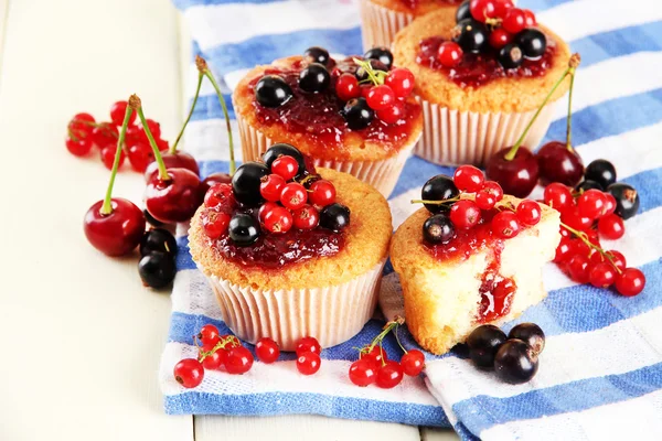 Smakelijke muffins met bessen op witte houten tafel — Stockfoto