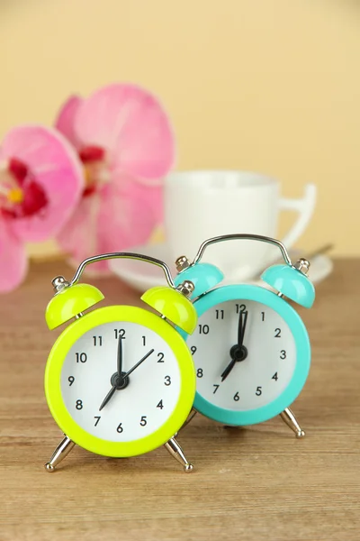 Reloj despertador colorido en la mesa sobre fondo beige — Foto de Stock