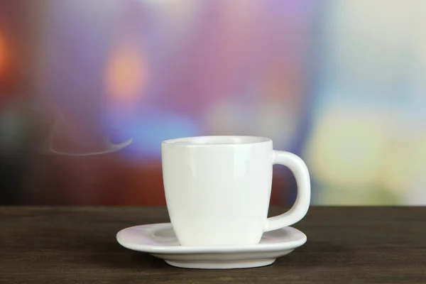 उज्ज्वल पृष्ठभूमि पर लकड़ी की मेज पर कॉफी का कप — स्टॉक फ़ोटो, इमेज