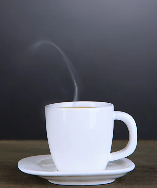 Taza de café sobre mesa de madera sobre fondo negro — Foto de Stock