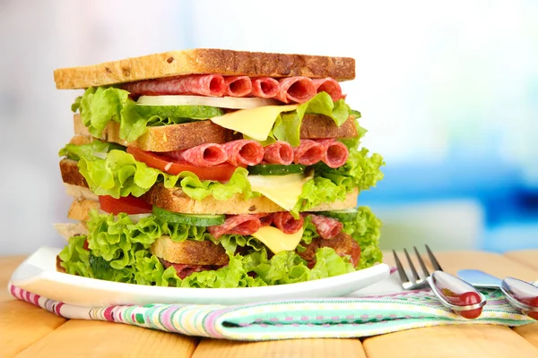Obrovské sendvič na dřevěný stůl, na světlé pozadí — Stock fotografie