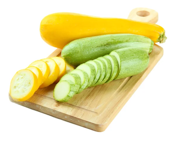 Gesneden en hele rauwe courgette op houten snijplank, geïsoleerd op wit — Stockfoto