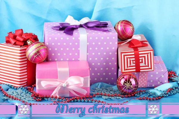 Colorful gifts with pink Christmas balls, snowflakes and beads on blue background — Stock Photo, Image