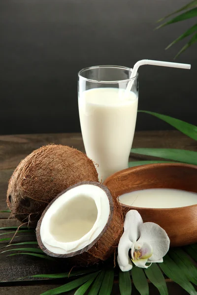 Noix de coco avec verre de lait, sur table en bois, sur fond gris — Photo